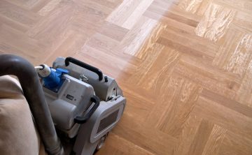 Sanding parquet with the grinding machine. Polishing, repair in Sanding hardwood floor with the grinding machine. Repair in the apartment. Carpenter doing parquet wood floor polishing maintenance work by grinding machine
